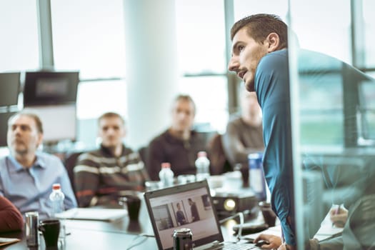 Business man making a presentation at office. Business executive delivering a presentation to his colleagues during meeting or in-house business training, explaining business plans to his employees.