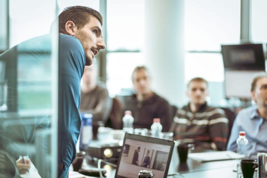 Business man making a presentation at office. Business executive delivering a presentation to his colleagues during meeting or in-house business training, explaining business plans to his employees.