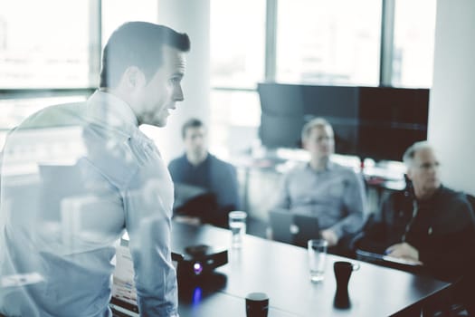Business man making a presentation at office. Business executive delivering a presentation to his colleagues during meeting or in-house business training, explaining business plans to his employees.