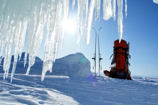 skier's backpack and skis in the snow. Icicles against the sky.