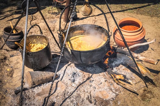 Stew or soup in iron pot or cauldron on a campfire. Homemade food at historical reenactment of Slavic or Vikings lifestyle from around 11th century, Cedynia, Poland