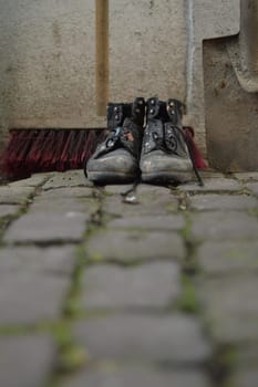 old worn painted work boots with a yard broom and a spade as symbol for cleaning, house keeper or maintenance
