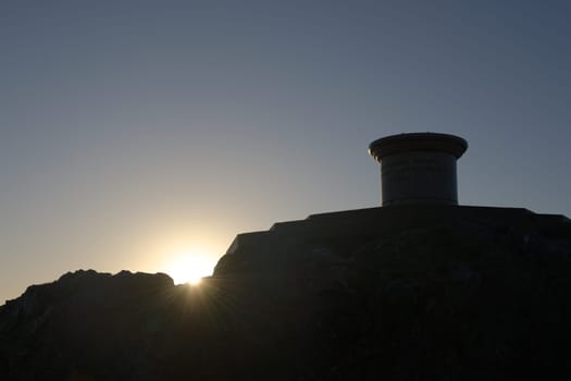 1 - Close up of malvern hills beacon toposcope at sunrise. A stone monument as part of the diamond jubilee in silhouetted profile. Plain sky.