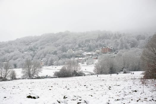 Malvern, United Kingdom, 28th December, 2020: Common land near Peachfield road as people walk, sledge and toboggan amongst fresh snow. Malvern hills