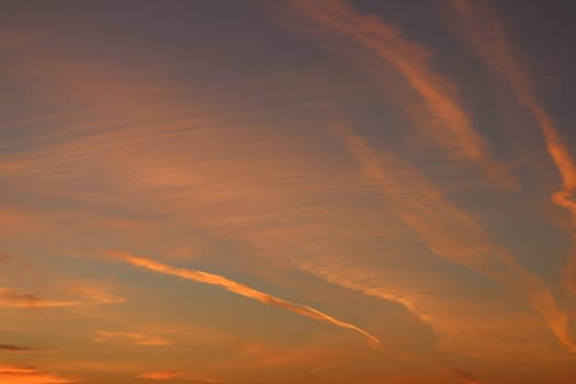 Red aircraft trails in the sky lit by the setting sun