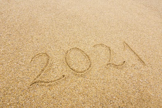 2021 handwritten on beach sand, new year and holiday concept