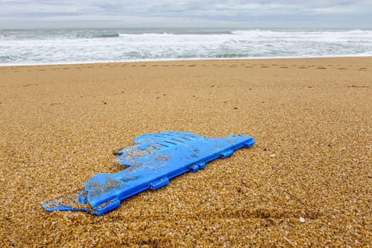 Big piece of blue plastic on beach, pollution concept, Atlantic Ocean in France