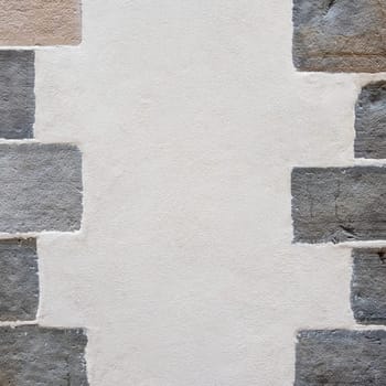 Plastered wall texture with stones on the sides, old renovated building detail shot