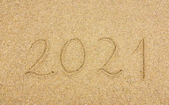 2021 handwritten on beach sand, new year and holiday concept