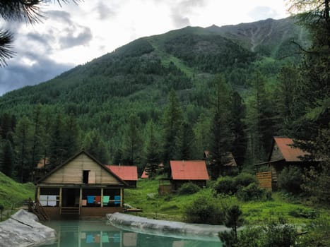 A small tourist base with wooden houses in the forests of the Altai Mountains.