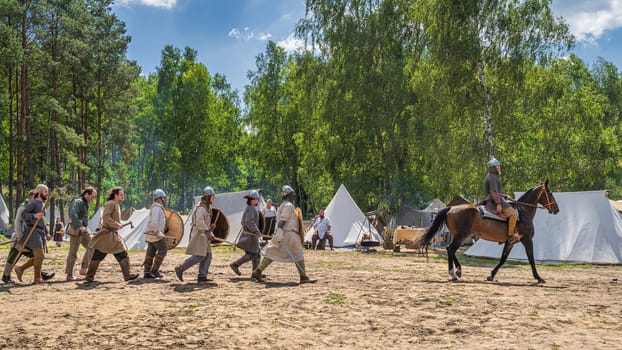 Cedynia, Poland, June 2019 Chieftain on the horse and his warriors passing tent camp. Historical reenactment of Battle of Cedynia between Poland and Germany, circa 11th century