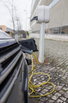 Petrol-electric hybrid car charging at urban charging station. Selective focus