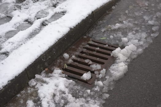 4 - Highway kerbside storm drain covered in melting snow. Winter seasonal weather in the month of december in the UK. Showing urban water management