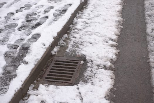 3 - Winter road scene with surface storm drain receiving the heavy water run off. Part of the december season weather in britain, bringing flood risk