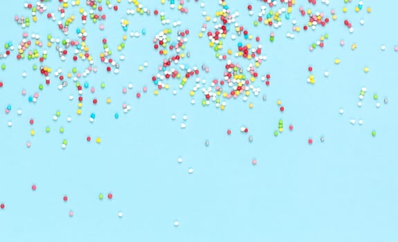 Multicolored candies for sweets on light blue background. Flat lay, copyspace, top view. Food concept. Banner.