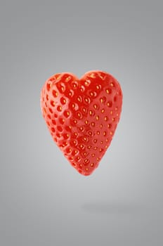 Minimal fruit concept. One whole strawberry fruit heart-shaped on ultimate gray background with shadow. Design element. Full depth of field. Valentine day.