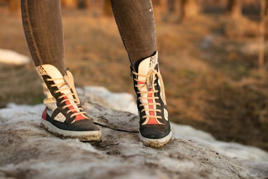 Fashion sneakers women's high bright leather and white rubber boots worn with jeans and both feet facing forward.