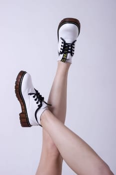 Female sneakers. White female shoes on feet.