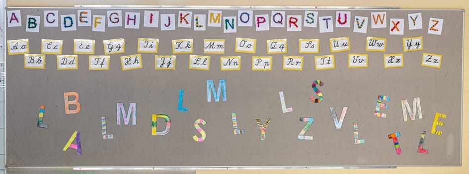 Colored letters, alphabet in block and cursive on the wall of a primary school
