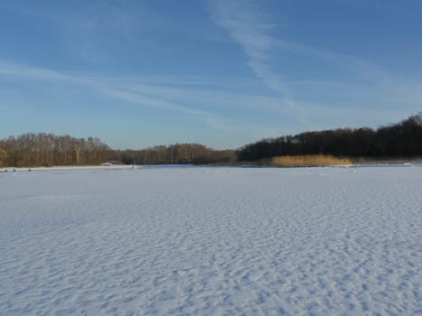 frozen lake clean flat snow forest on the horizon, winter landscape