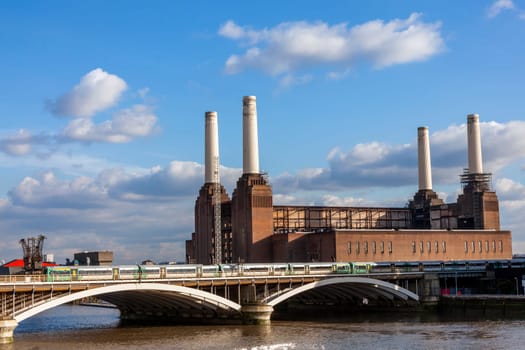 Battersea Power Station in London England UK a coal fired building built in 1935 on the River Thames with a passing railway train showing public transport infrastructure, stock photo image