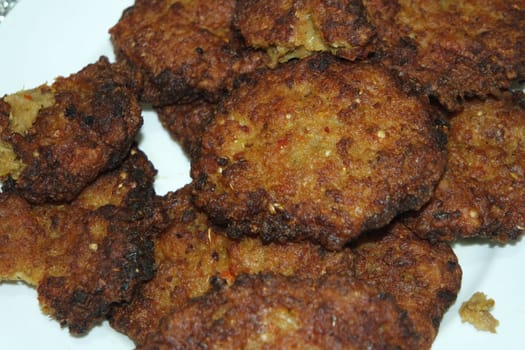 Delicious spicy fried round kebab served in a white ceramic plate on wooden floor