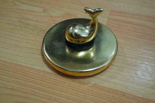 The decorative little golden pot with dolphin lid open, for room decoration. Golden pot on the vintage white background.