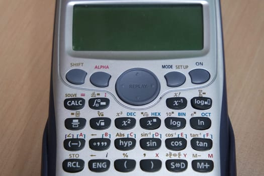 Calculator with colored keys or buttons isolated on a wooden background
