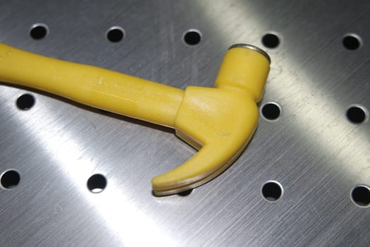 Selective focused, closeup view of toy hammer made from plastic placed on metal background