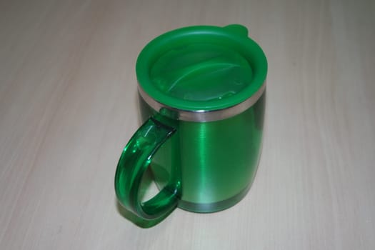 Beautiful coffee green hot mug with green led, placed over white floor. Closeup perspective view of a mug on white desk.