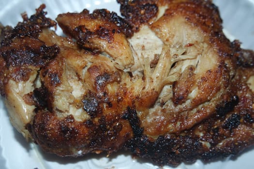 Close up of roasted chicken pieces in a white plate served for meal. Meat background for restaurant advertisements