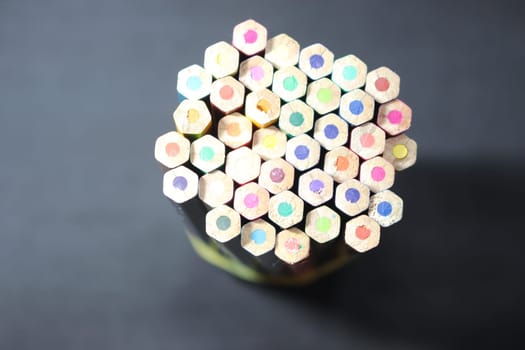 Close-up view of bright colored multicolor pencils on black background