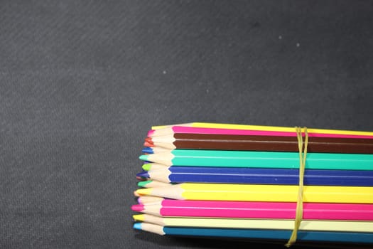 Close-up view of bright colored multicolor pencils on black background
