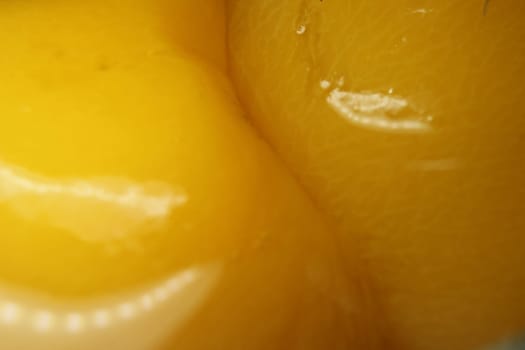 Closeup view with selective focus of yellow peaches slices. Canned peaches halves sprinkled with syrup.