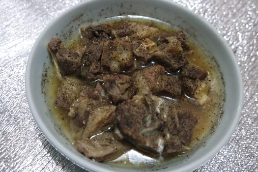 Top view of siri paaye or paya dish garnished with diced ginger, long coriander and black pepper. This dish is popular in Pakistan and Bangladesh