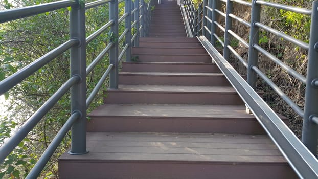 Wooden stairs with handrails on both sides in a park.
