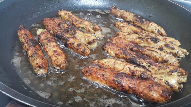 Delicious spicy fried long kebab served in black hot plate with boiling oil