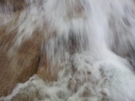 Blurred or unfocused view of flowing water stream in between stones. Flowing water background for texture and advertisements