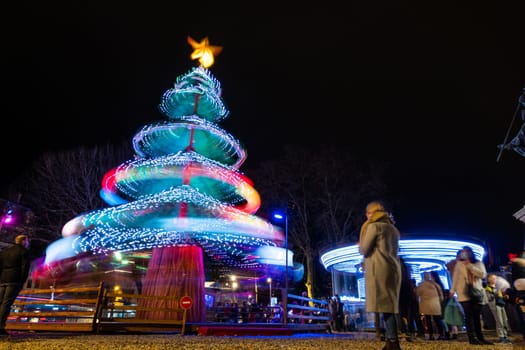 BAYONNE, FRANCE - CIRCA DECEMBER 2020: Long exposure of a Christmas tree carousel and a merry-go-round at night. Low angle shot with motion blur.