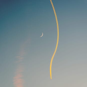 Jet airplane, its contrail and a crescent moon at sunset. The plane seems to go around the moon. Square crop.