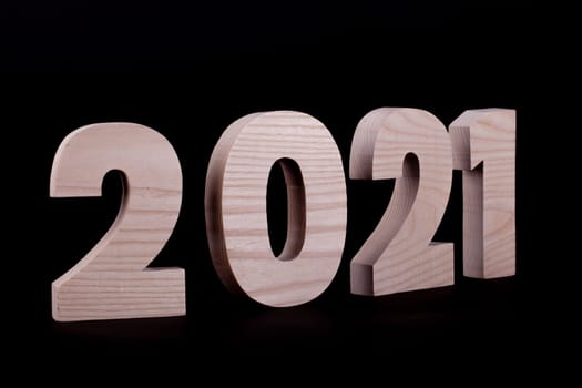 2021 year large wooden numbers at an angle. Hardwood characters on a black background