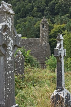 Glendalough, co. Wicklow, Ireland - August 10 2019 :Stone round tower and some ruins of a monastic settlement originally built in the 6th century in Glendalough valley, County Wicklow, Ireland.