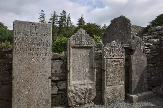Glendalough, co. Wicklow, Ireland - August 10 2019 :Stone round tower and some ruins of a monastic settlement originally built in the 6th century in Glendalough valley, County Wicklow, Ireland.