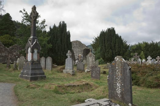 Glendalough, co. Wicklow, Ireland - August 10 2019 :Stone round tower and some ruins of a monastic settlement originally built in the 6th century in Glendalough valley, County Wicklow, Ireland.