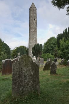 Glendalough, co. Wicklow, Ireland - August 10 2019 :Stone round tower and some ruins of a monastic settlement originally built in the 6th century in Glendalough valley, County Wicklow, Ireland.