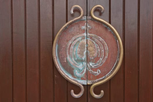 Medieval metal handle and doorknob on a wooden door.