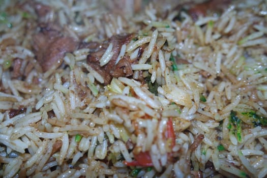 A close up view with selective focus of cooked white Basmati rice pulao or biryani with chicken meat