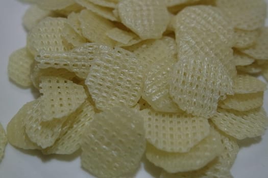 Closeup view with selective focus on dried chips as fast food for tea break. Potato chips with spices sprinkled on it. Fast food background for advertisements.