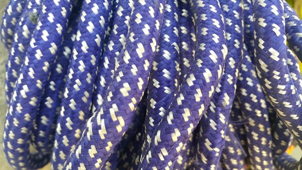 Closeup of bright color braided plastic ropes. Hanks or coil of bright colored plastic rope interwoven which are used for climbing and tightening materials.