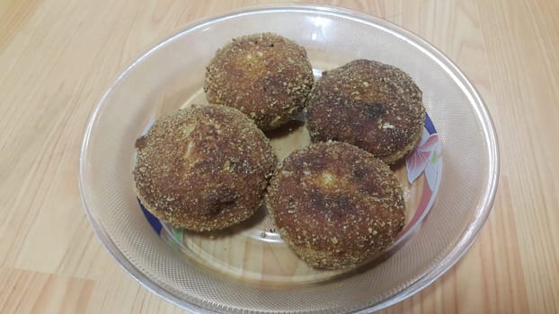 Closeup perspective view of fried pizza bomb or pizza balls served in a glass plate over wooden floor. Pizza bombs are delicious and tasty altered form of pizza.